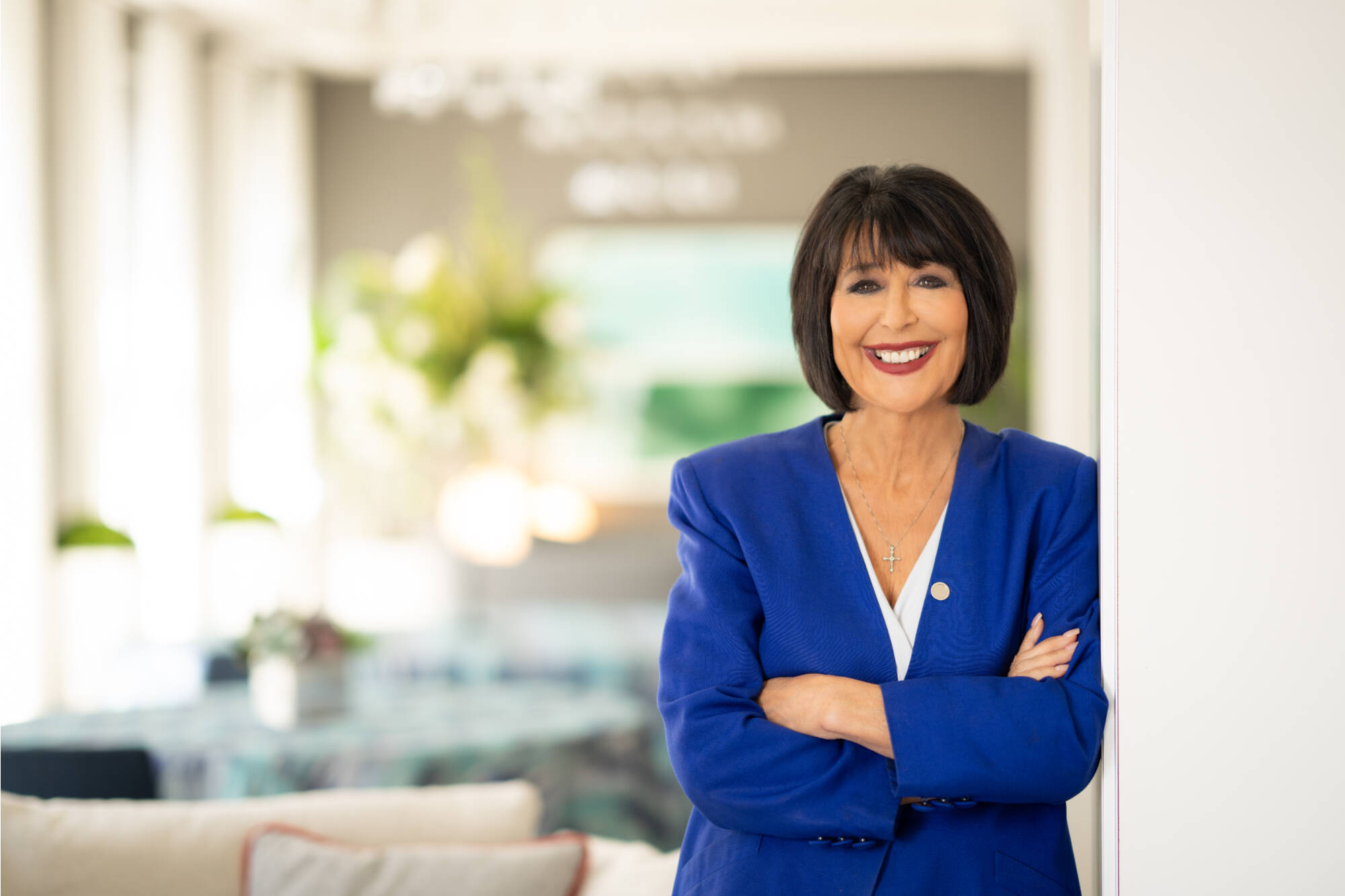 GVSU President Philomena V. Mantella leaning against wall with her arms crossed and a smile on her face.